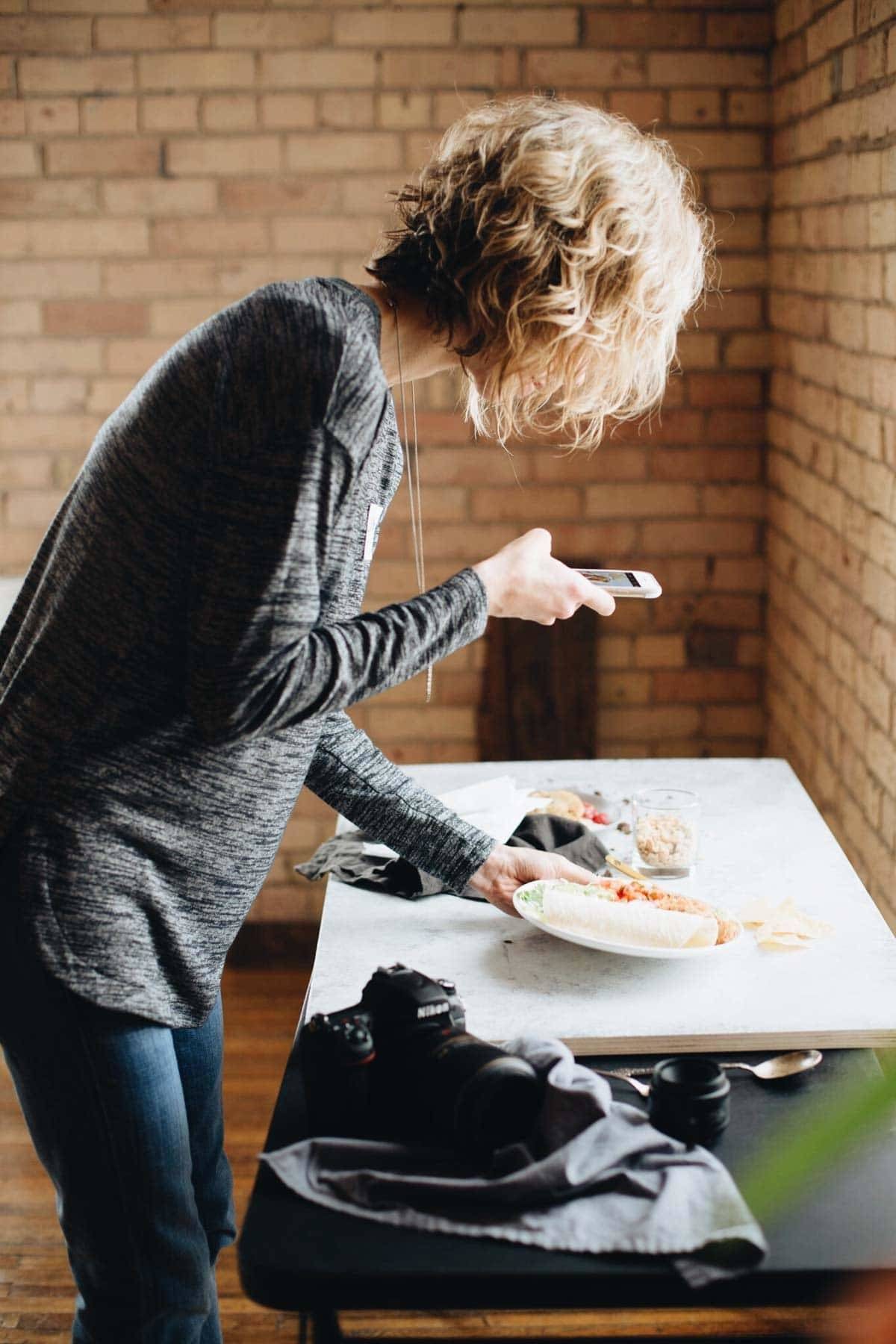 Woman taking a photo of food with an iphone.